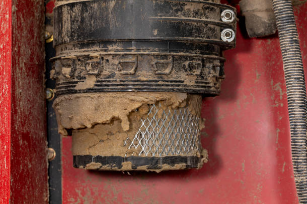 A cylindrical filter caked in dried mud before cleaning